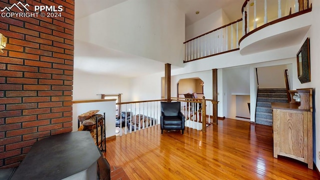 corridor with a towering ceiling, brick wall, and hardwood / wood-style floors