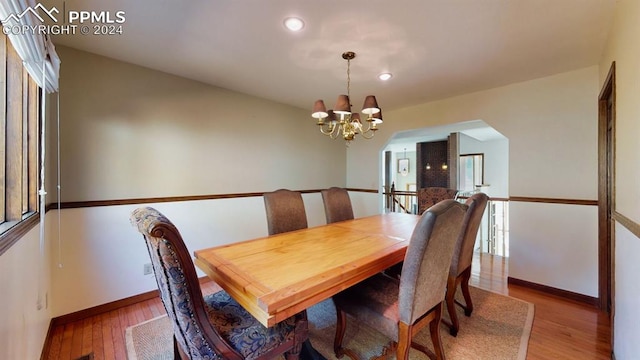 dining area with hardwood / wood-style floors and an inviting chandelier