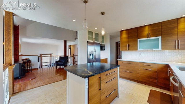 kitchen with appliances with stainless steel finishes, hanging light fixtures, light tile patterned floors, decorative backsplash, and a kitchen island