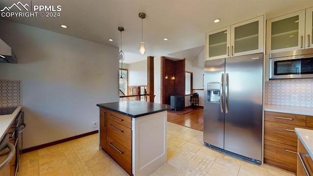 kitchen with appliances with stainless steel finishes, white cabinets, a kitchen island, backsplash, and light hardwood / wood-style floors