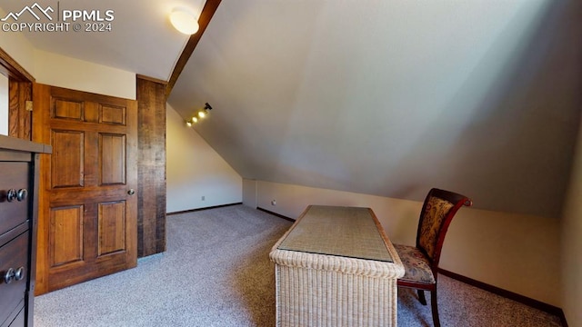 carpeted home office featuring vaulted ceiling