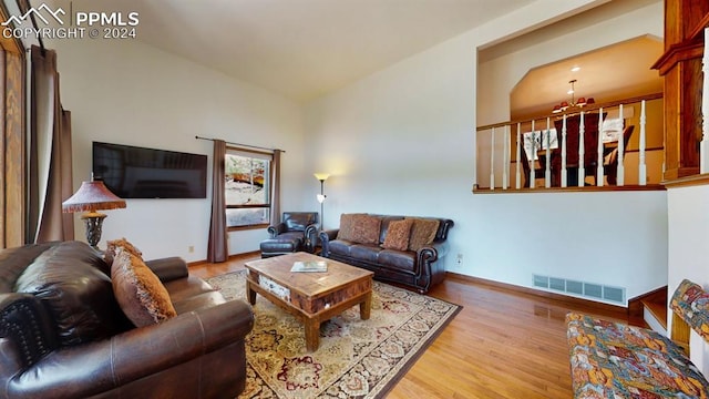 living room featuring lofted ceiling, light hardwood / wood-style flooring, and a chandelier