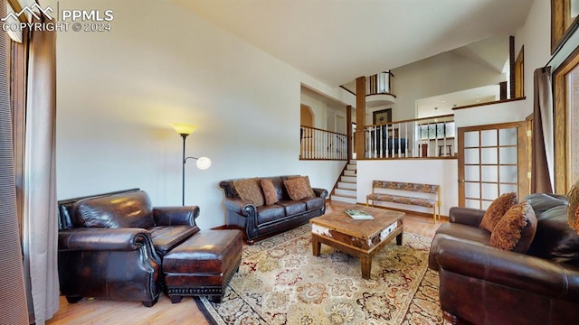 living room featuring light wood-type flooring and a towering ceiling