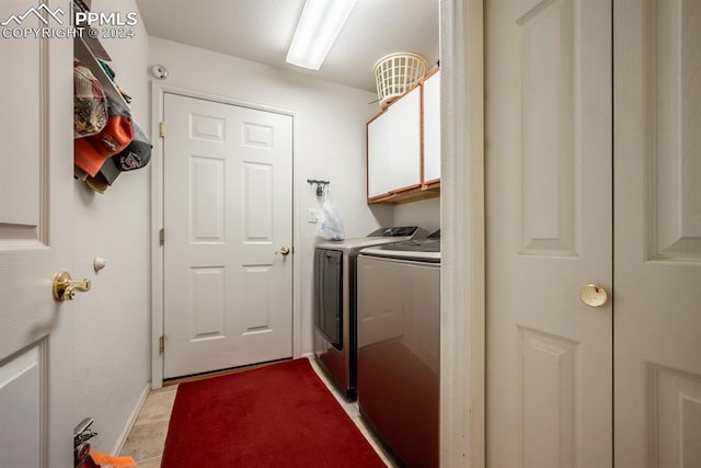 washroom featuring light tile patterned flooring, independent washer and dryer, and cabinets