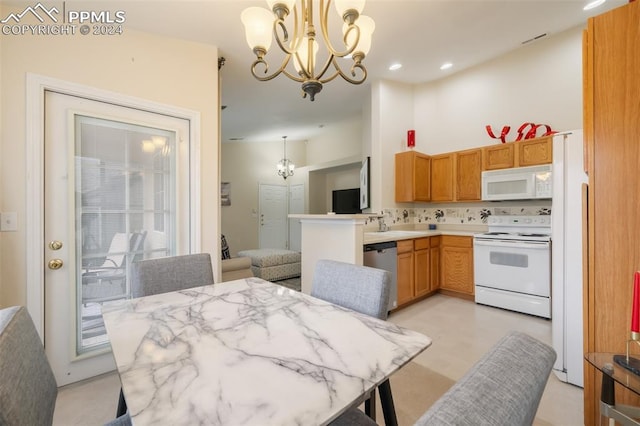 kitchen with kitchen peninsula, a notable chandelier, white appliances, and decorative light fixtures