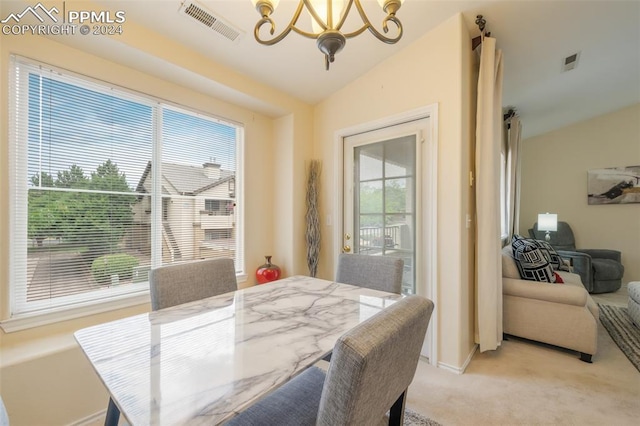 carpeted dining area with vaulted ceiling and a notable chandelier