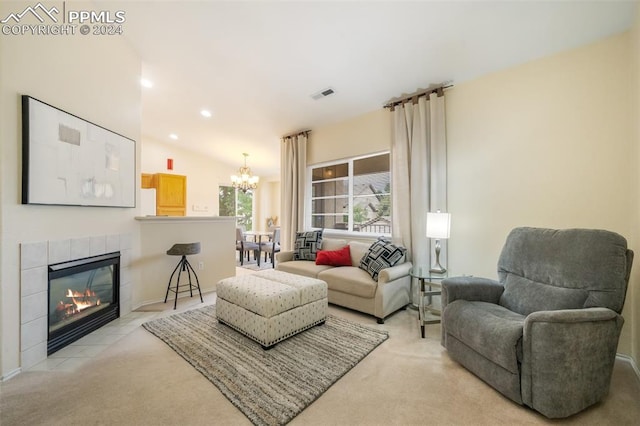 carpeted living room featuring a tile fireplace, lofted ceiling, and a notable chandelier