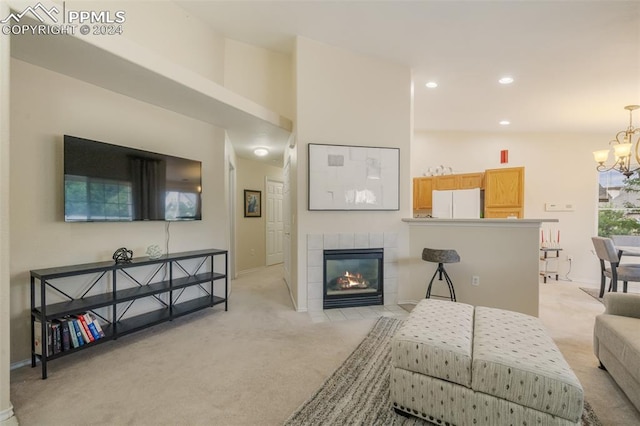 living room with a tile fireplace, light carpet, and a notable chandelier