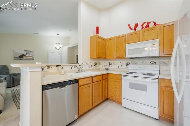 kitchen featuring sink, hanging light fixtures, a notable chandelier, kitchen peninsula, and white appliances