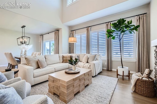 living room with light wood-type flooring, an inviting chandelier, and a wealth of natural light