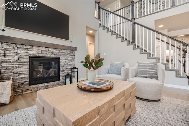 living room featuring light hardwood / wood-style floors, a fireplace, and a towering ceiling