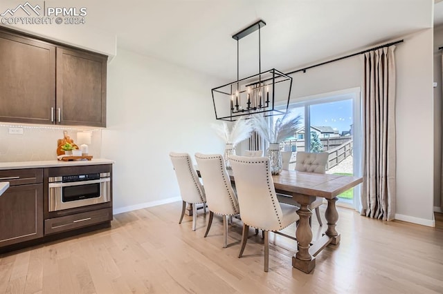 dining space with light hardwood / wood-style flooring and a notable chandelier