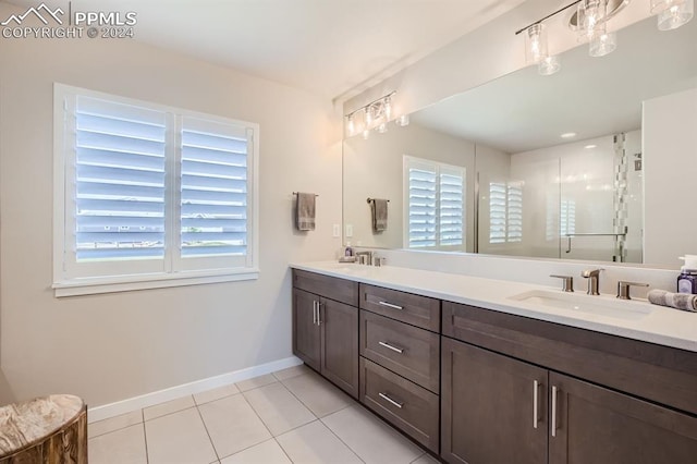 bathroom featuring tile patterned floors, vanity, a shower with shower door, and a wealth of natural light