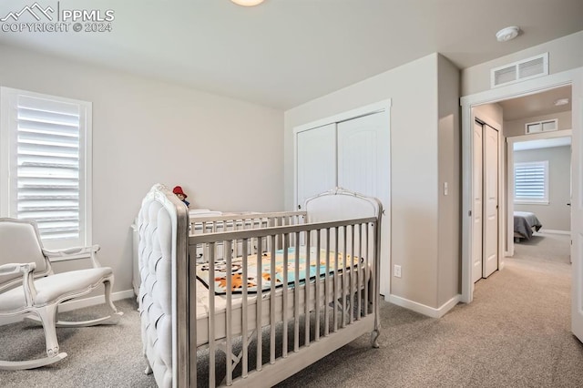 carpeted bedroom featuring a nursery area and a closet