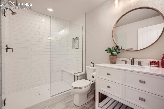 bathroom featuring vanity, a shower with shower door, and toilet