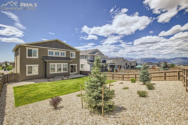 rear view of house with a mountain view, a lawn, and a patio