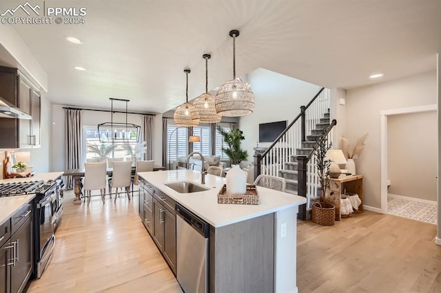 kitchen featuring an island with sink, appliances with stainless steel finishes, sink, and light hardwood / wood-style flooring