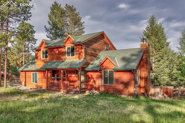 back of property with covered porch and a lawn