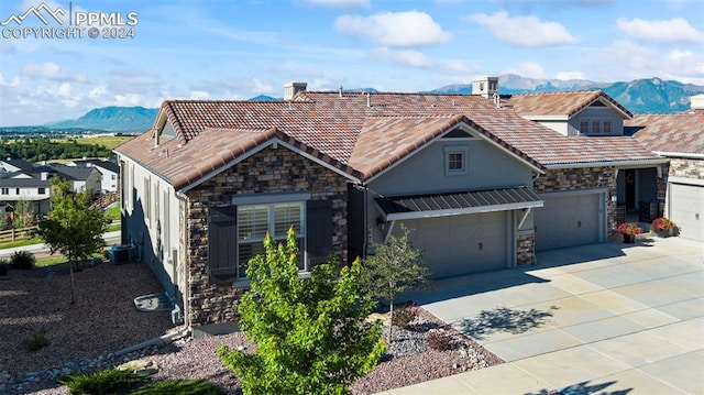 view of front facade featuring a mountain view, central AC, and a garage