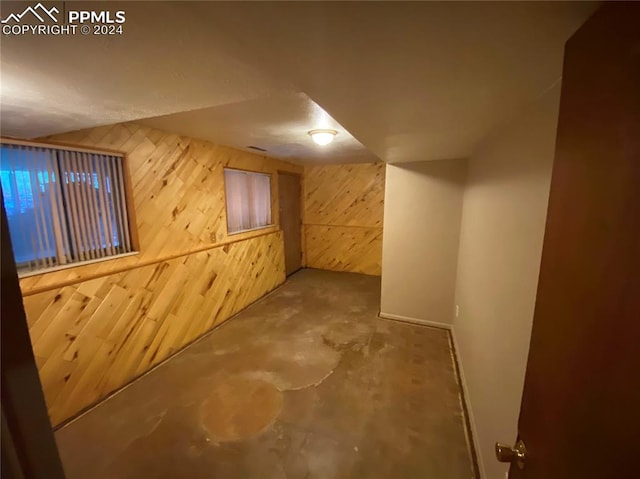 bonus room with concrete floors and wooden walls