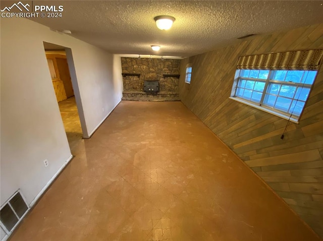 unfurnished living room with wood walls, a textured ceiling, and tile patterned floors