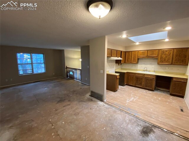 kitchen featuring a textured ceiling, sink, and a skylight