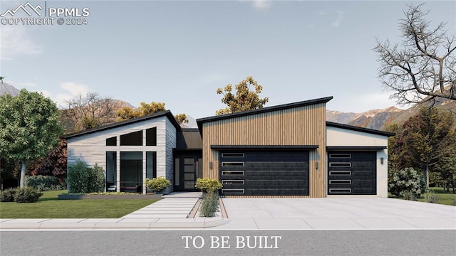 modern home with a garage, a front lawn, and a mountain view