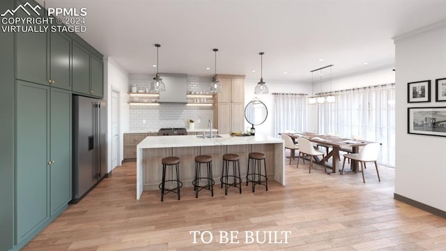 kitchen featuring decorative backsplash, hanging light fixtures, appliances with stainless steel finishes, a kitchen island with sink, and light hardwood / wood-style floors