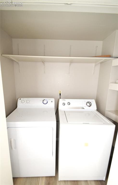 clothes washing area with washer and dryer and light hardwood / wood-style floors