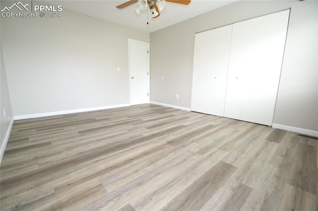 unfurnished bedroom with a closet, light wood-type flooring, and ceiling fan