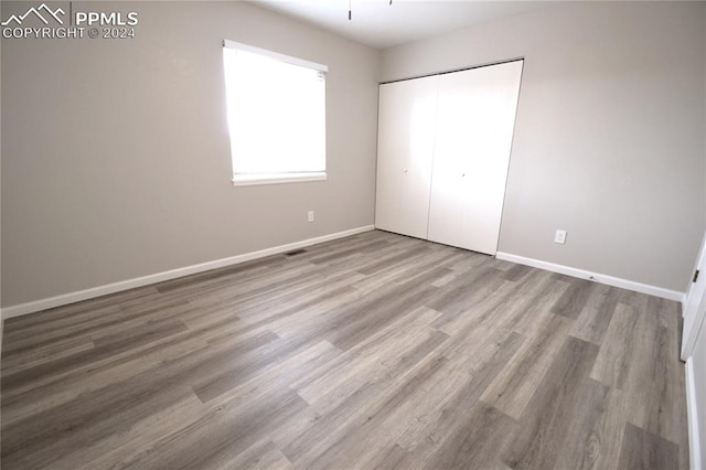 unfurnished bedroom with hardwood / wood-style floors and a closet