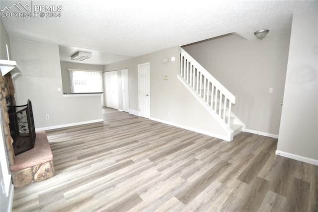 unfurnished living room featuring a textured ceiling, a fireplace, and hardwood / wood-style floors