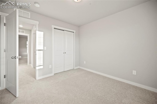 unfurnished bedroom featuring light carpet and a closet