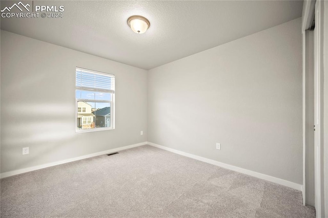 carpeted empty room featuring a textured ceiling