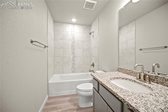 full bathroom featuring hardwood / wood-style floors, vanity, toilet, and tiled shower / bath