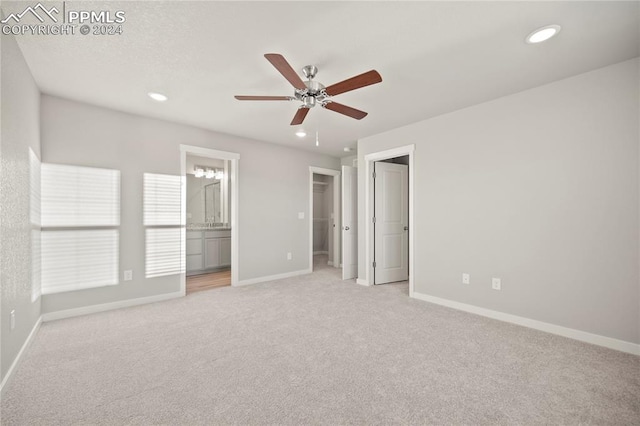 unfurnished bedroom with ensuite bathroom, ceiling fan, and light colored carpet