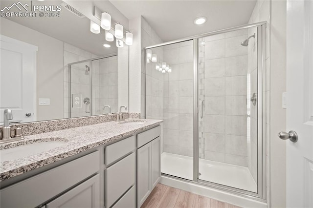 bathroom with a shower with shower door, wood-type flooring, and vanity