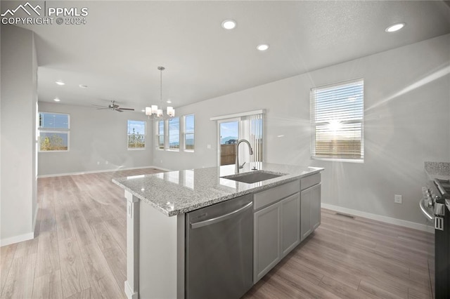 kitchen with an island with sink, stainless steel appliances, light hardwood / wood-style floors, and sink