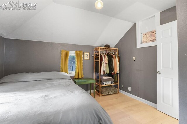 bedroom with vaulted ceiling, a closet, and light wood-type flooring