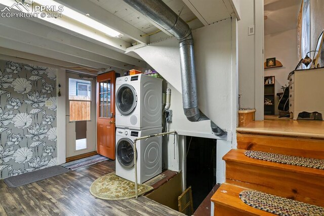 clothes washing area featuring dark hardwood / wood-style floors and stacked washer and clothes dryer