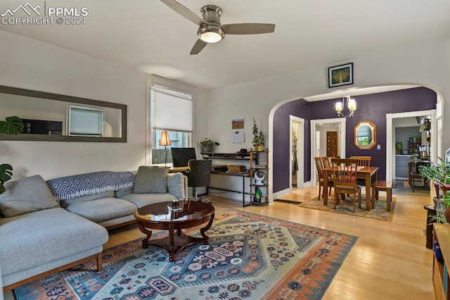 living room with ceiling fan with notable chandelier and light hardwood / wood-style floors