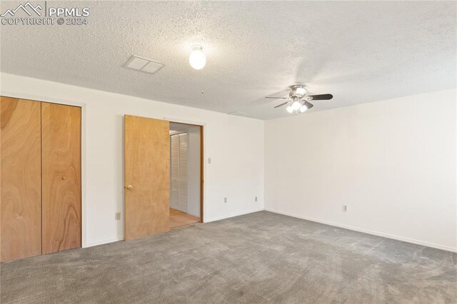 carpeted empty room with ceiling fan and a textured ceiling