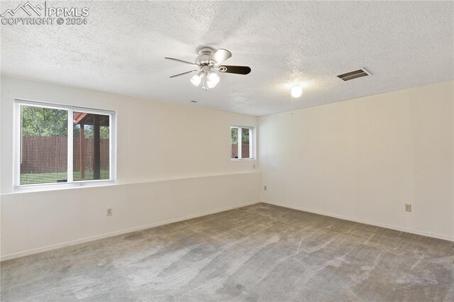 empty room with light carpet, a textured ceiling, and ceiling fan