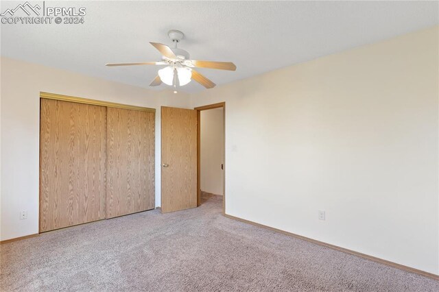 unfurnished bedroom featuring carpet, ceiling fan, and a closet