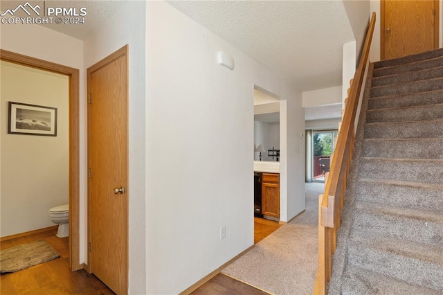 staircase with hardwood / wood-style flooring and a textured ceiling