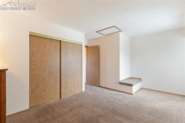 unfurnished bedroom featuring carpet floors, a textured ceiling, and a closet