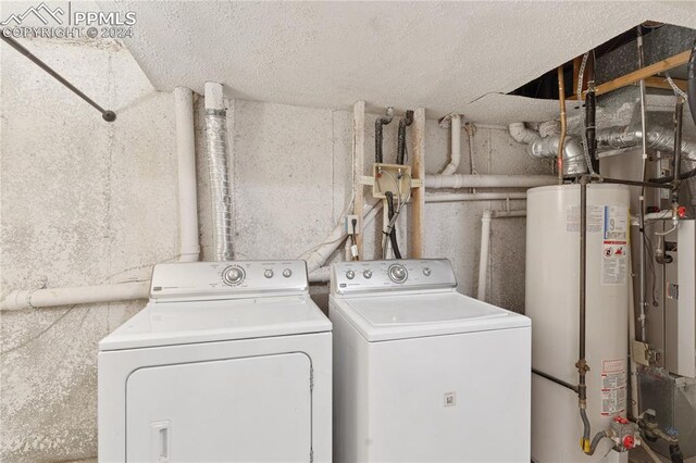 washroom with water heater and washing machine and dryer