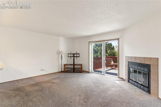 unfurnished living room featuring light carpet, a tile fireplace, and a textured ceiling