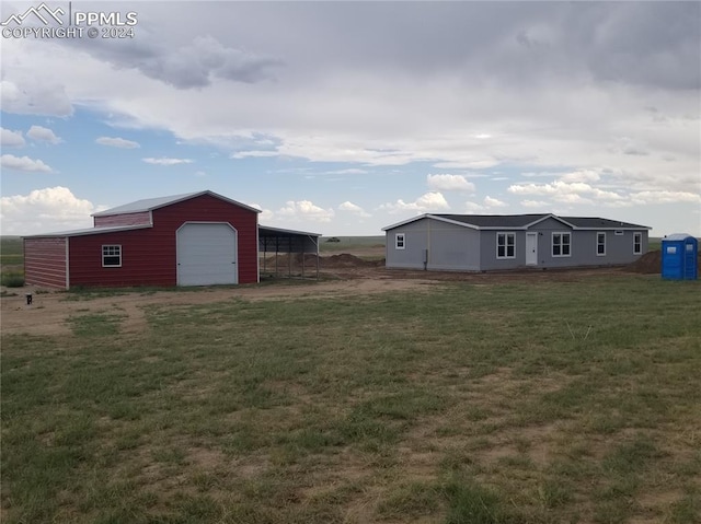 view of yard with a carport, a garage, and an outdoor structure