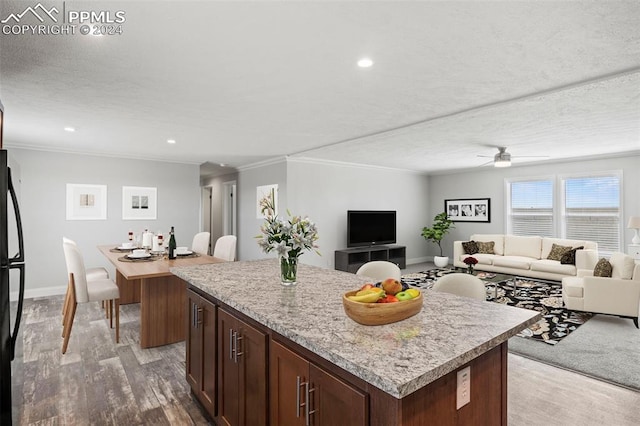 kitchen with ornamental molding, a textured ceiling, ceiling fan, light hardwood / wood-style flooring, and a center island